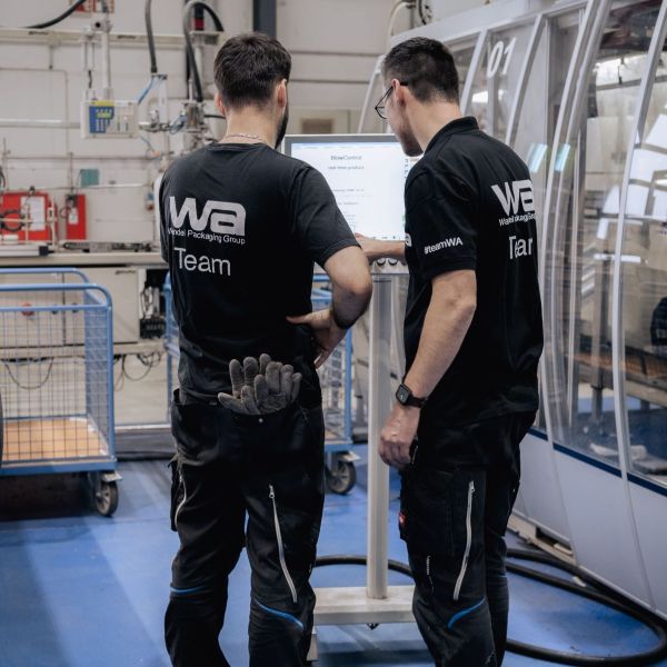 Zwei Kollegen bei der Bedienung einer Maschine